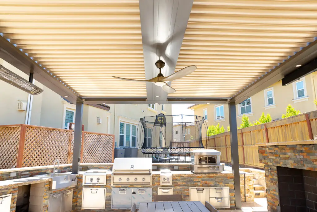 Outdoor kitchen with built-in pizza oven under a StruXure pergola in a Danville, CA backyard