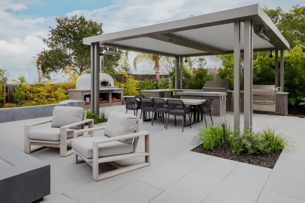 Dining table and lounge seating near a wood-fired pizza oven in Emerald Hills, CA
