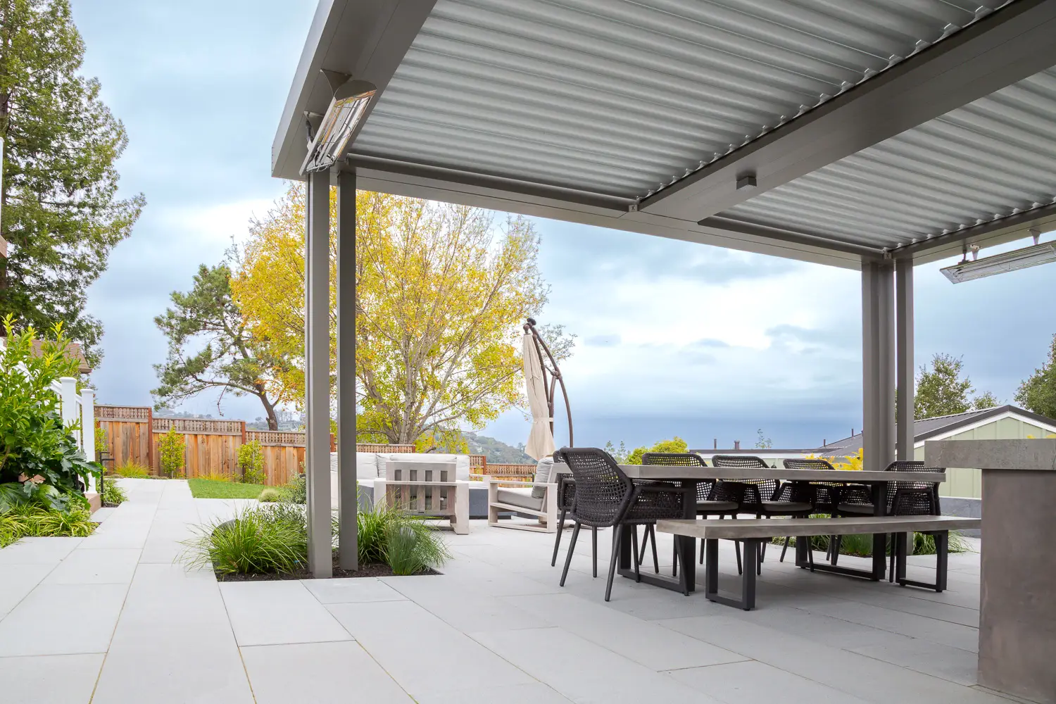 Motorized StruXure pergola over a dining and lounge area with hillside views in Emerald Hills, CA