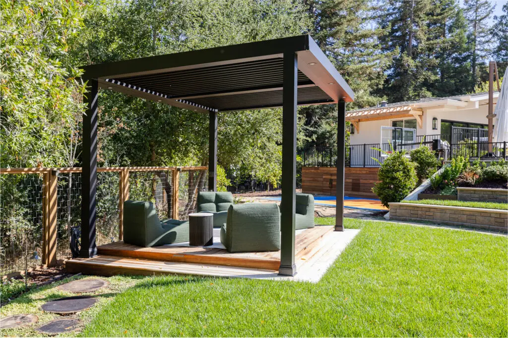 StruXure pergola in a yard corner framed by stone retaining walls and redwoods in Saratoga, CA