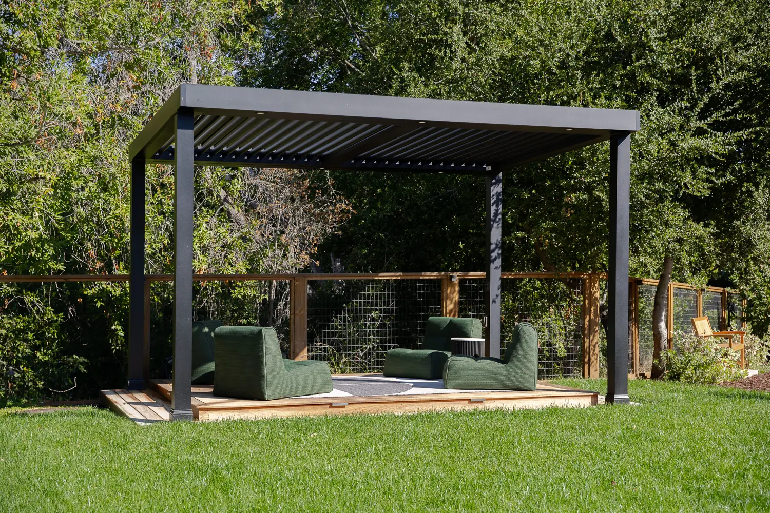Freestanding motorized StruXure pergola on a raised deck at the edge of a lawn in Saratoga, CA